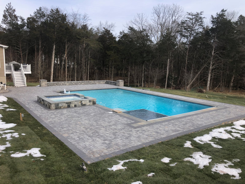 Paver pool deck with hot tub and seating wall.  Wallstone columns. 