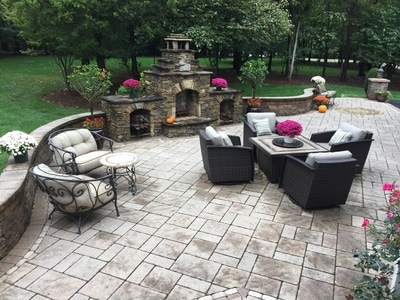 Large tile paver patio with seating wall and stone fireplace. 