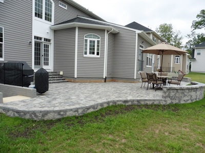 Paver patio with footer wall.  Patio steps with bullnose.  Paver seating wall with capstone.
