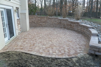 Paver patio with large retaining wall and raised beds. 