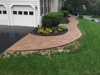 Curved paver walkway from the driveway to the front door.  Landscaping. 