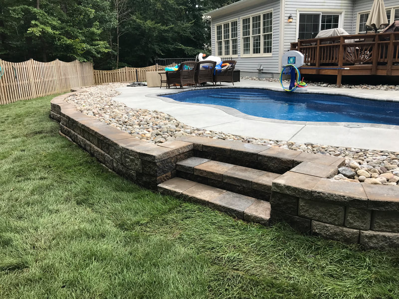 Paver wallstone wall and riverrock around in ground pool. 