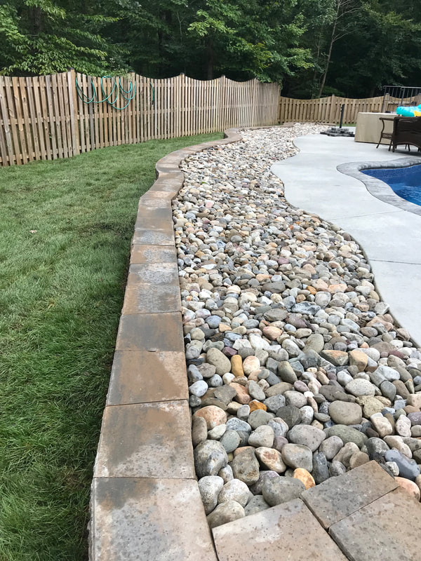 Riverrock drainage bed and paver retaining wall. 