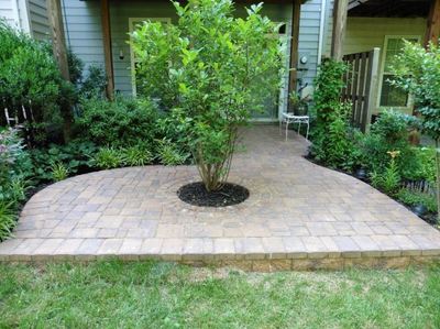 Paver patio under deck with circle kit and tree. 
